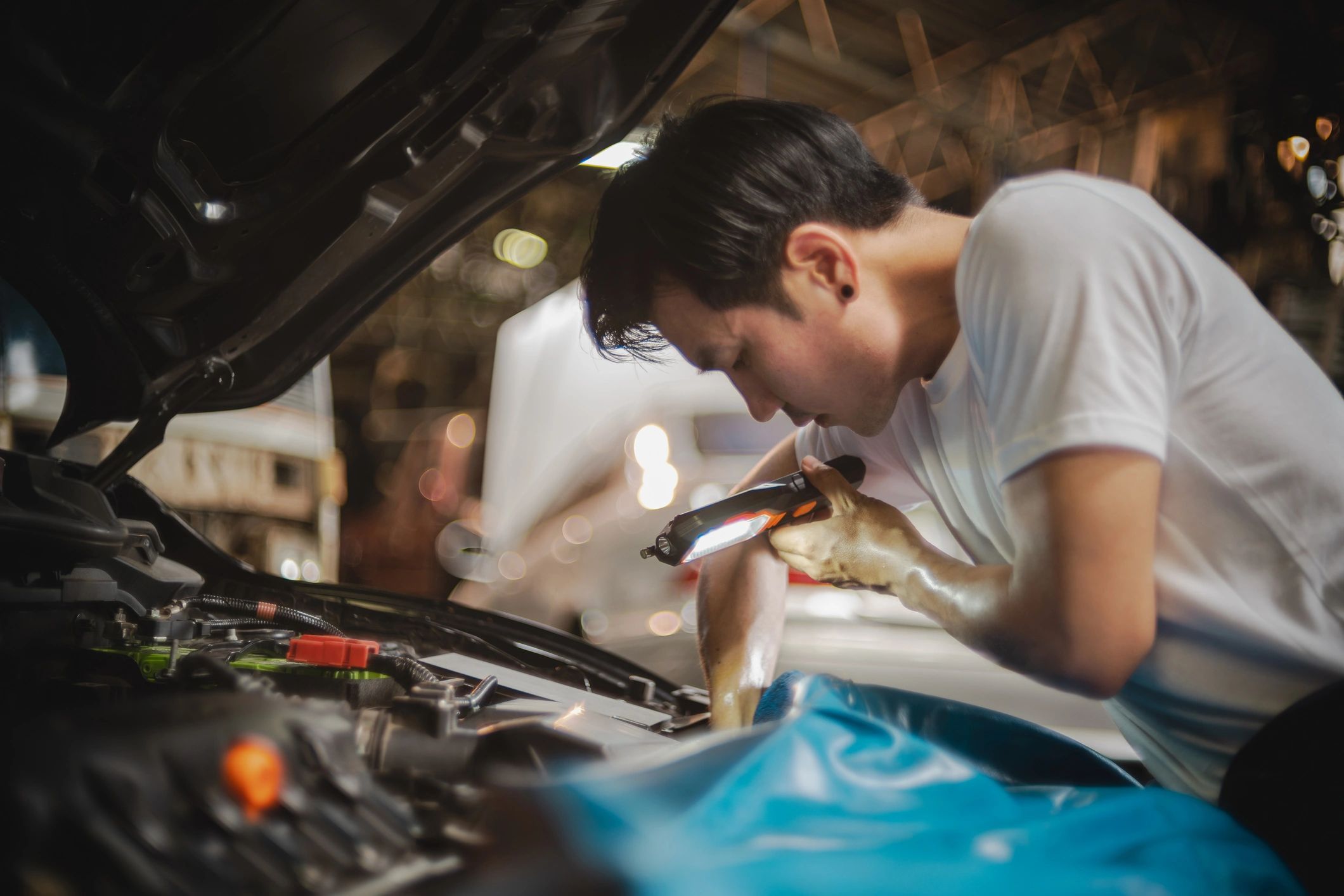 Mechanic inspecting a vehicle engine bay with focused attention