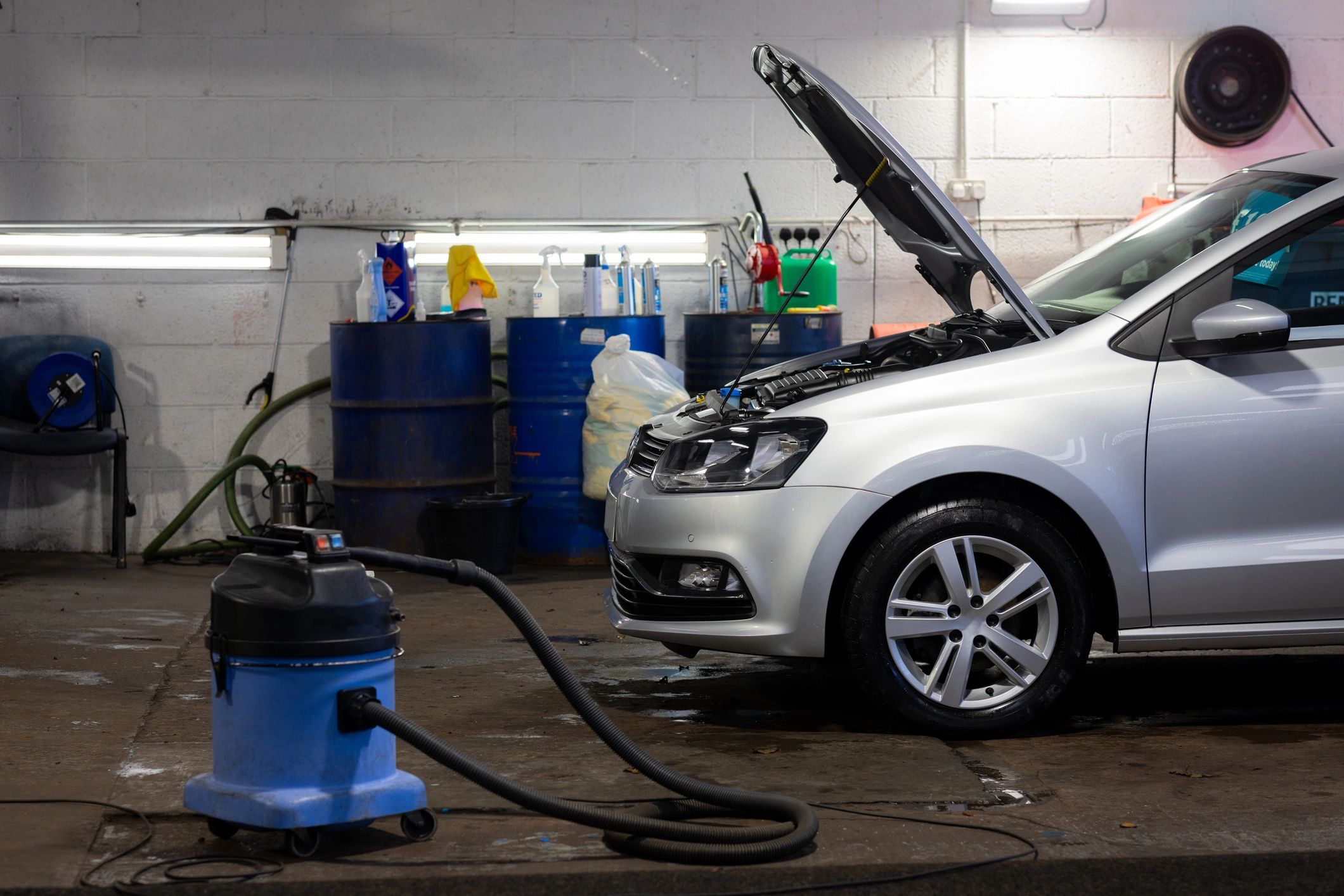 Silver car being serviced inside an automotive garage